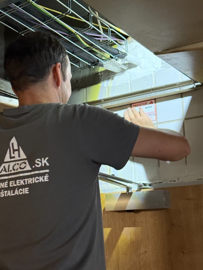 Technik ALCO pri montáži alebo kontrole certifikovaného požiarneho prestupu – káblové trinky, štítok PRESTUP. ALCO.SK.