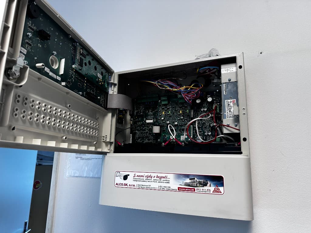 Otvorená ústredňa EPS – obvodové dosky, kabeláž a napájací zdroj. Nálepka ALCO.SK, s.r.o. – zabezpečenie objektov, kamerové systémy, revízie VTZ-E, ochrana vozidiel. Elektrická požiarna signalizácia.