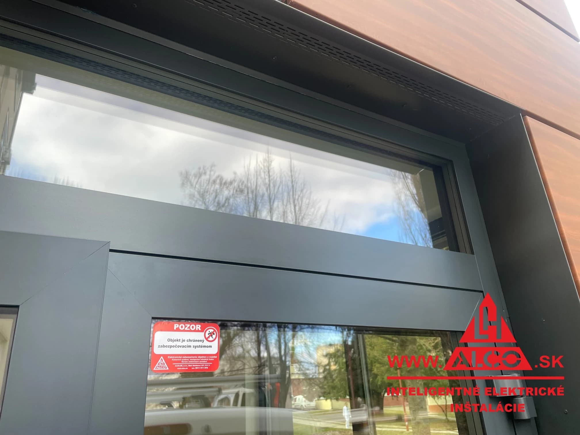 Nálepka Objekt je chránený zabezpečovacím systémom – priestory bufetu Fakultnej nemocnice Trenčín. ALCO.SK.
