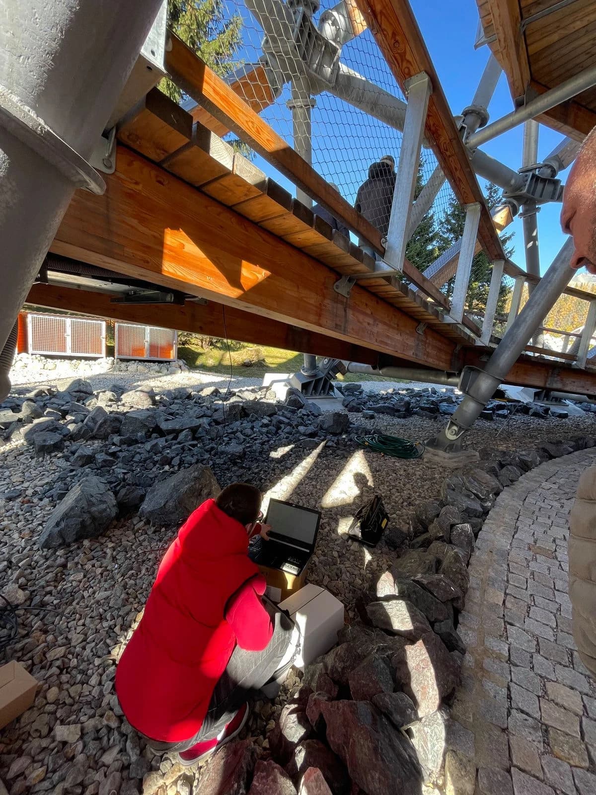 Konfigurácia a testovanie pod vežou – technik pri laptopu, výstupová trasa v pozadí, Štrbské pleso. ALCO.SK.