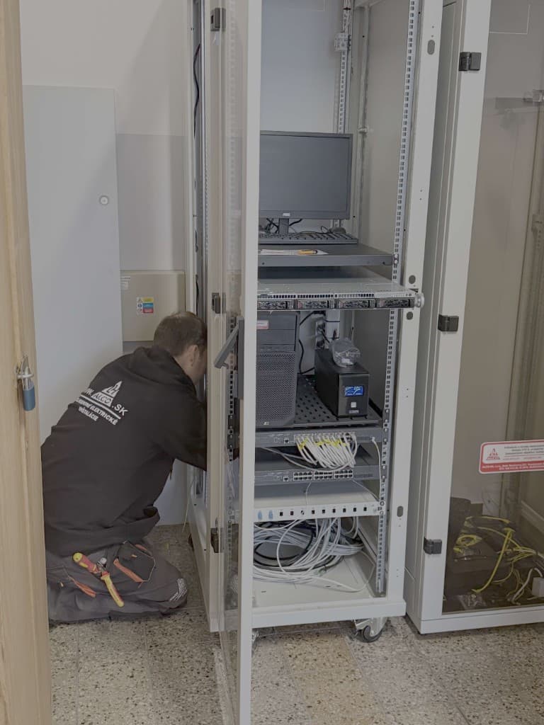 Technik ALCO.SK pri montáži a zapájaní v technickej miestnosti – serverový rack, napájanie a sieť pri realizácii zabezpečovacích systémov. ALCO.SK.